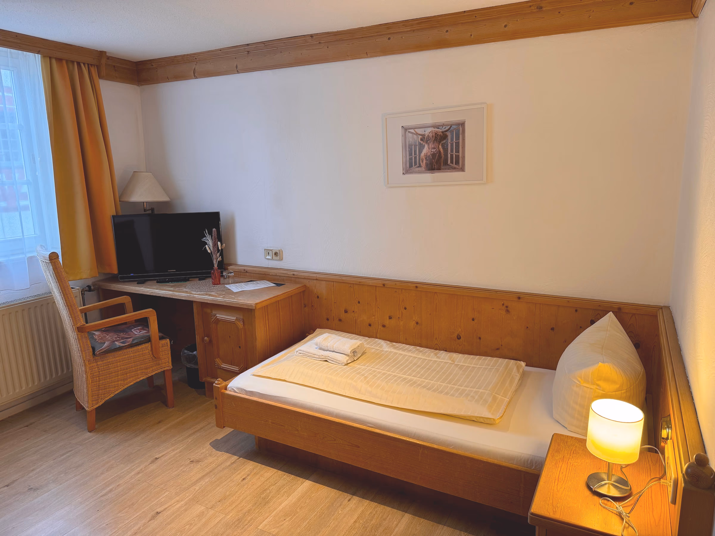 Einzelzimmer im Historikhotel Ochsen mit Holzbett, Schreibtisch und warmer Nachttischlampe